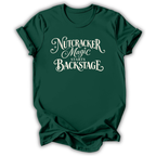 A dark green short-sleeve t-shirt with a white graphic text print reading 'Nutcracker Magic Starts Backstage' on the front, displayed against a clean white background.