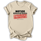 A beige short-sleeve t-shirt with a graphic print that reads 'NOTICE Rehearsal Season: ATTENDANCE MANDATORY' in black and red text, displayed on a clean white background.