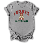 A heather gray short-sleeve t-shirt with a graphic print of a nutcracker and the text 'NUTCRACKER IS MY SPORT' in red and green.