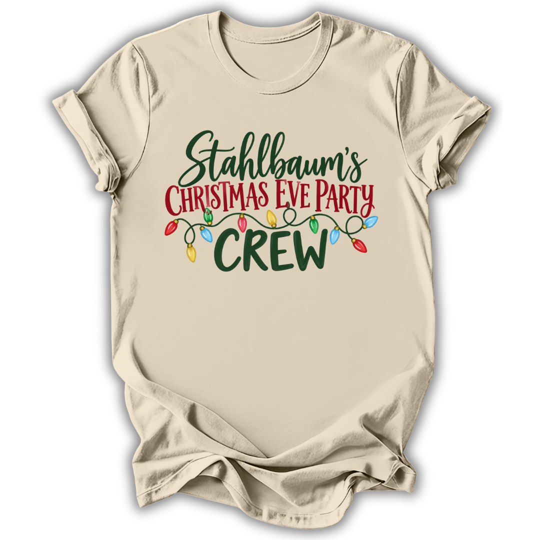 A beige short-sleeve t-shirt with a graphic print that reads 'Stahlbaum's Christmas Eve Party CREW' in green and red lettering, decorated with a string of multicolored Christmas lights, shown on a white background.
