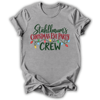 A heather gray short-sleeve t-shirt with a festive graphic on the front that reads 'Stahlbaum's Christmas Eve Party CREW' in green and red lettering, decorated with colorful Christmas lights.