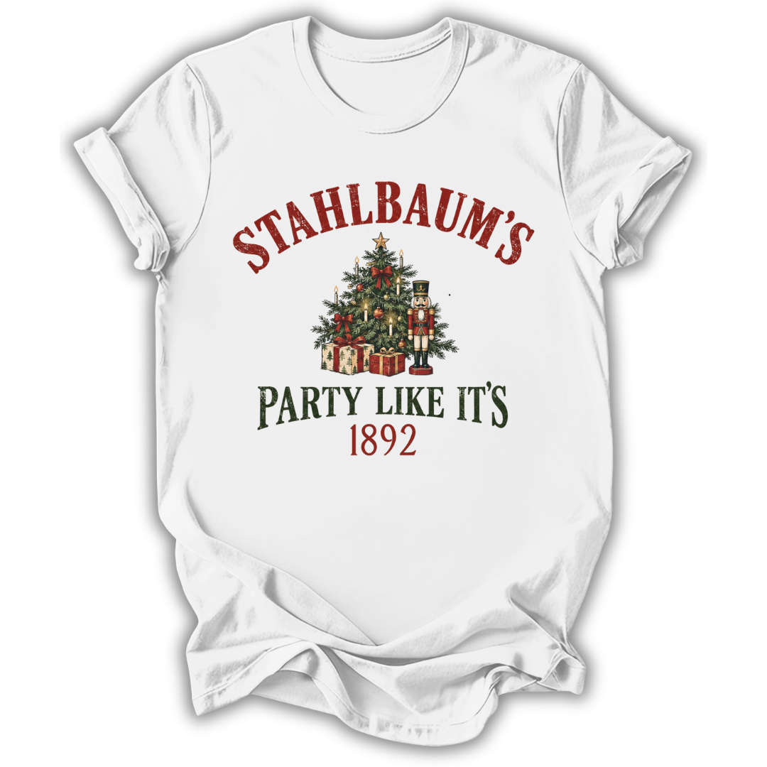 A white short-sleeve t-shirt with a Christmas-themed graphic print. The design features the text 'STAHLBAUM'S PARTY LIKE IT'S 1892' in red and dark green lettering, surrounding an illustration of a decorated Christmas tree with gifts and nutcrackers.