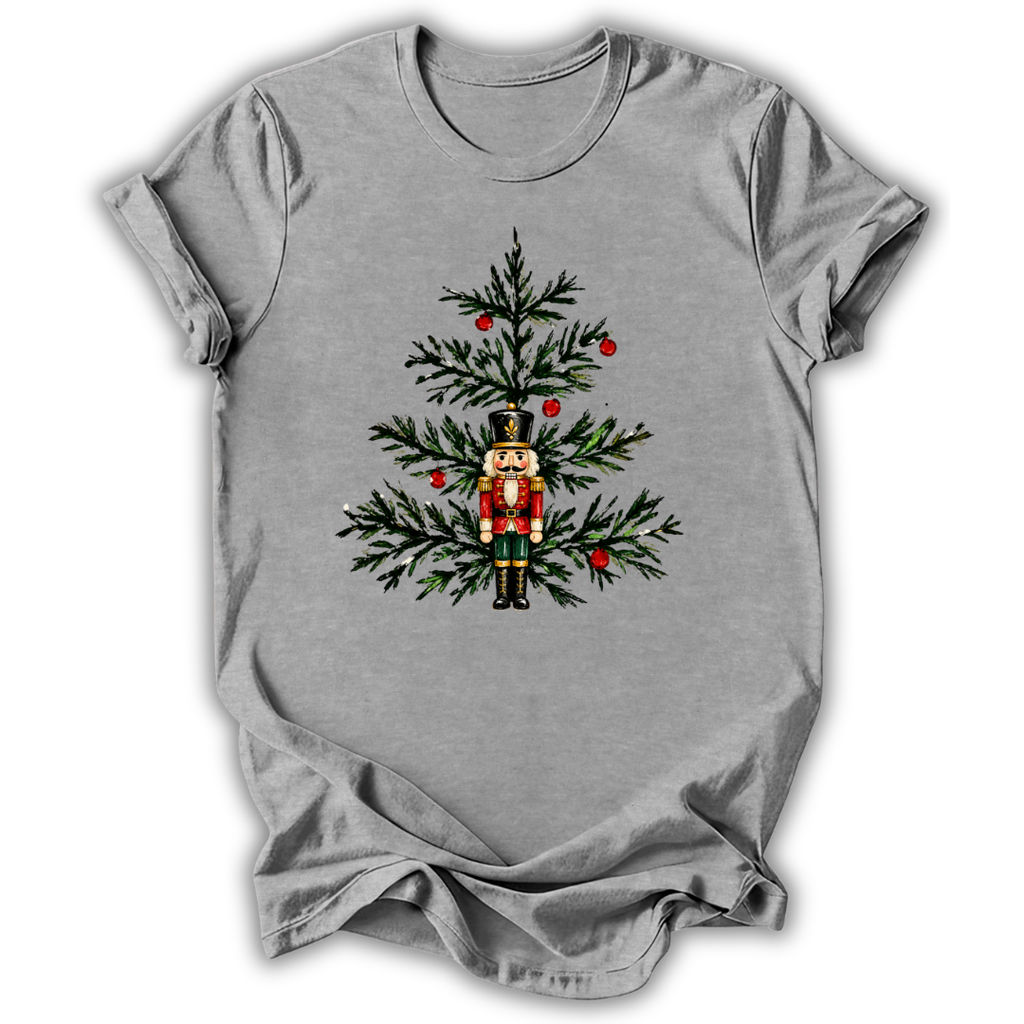 A heather gray short-sleeve t-shirt with a graphic of a nutcracker standing in front of a decorated Christmas tree, shown on a plain white background.