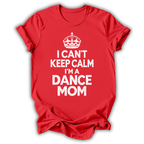 A red short-sleeve crewneck t-shirt with a white graphic print on the front featuring a crown and the text 'I CAN'T KEEP CALM I'M A DANCE MOM'.