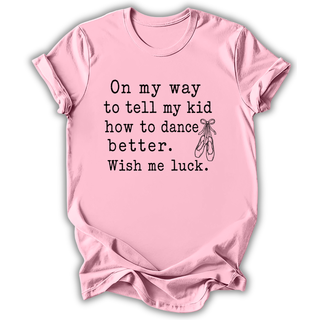 A light pink short-sleeve crewneck t-shirt with black printed text that reads 'On my way to tell my kid how to dance better. Wish me luck.