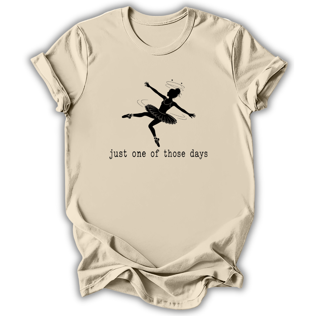 A beige short-sleeve t-shirt with a black graphic of a ballerina and the text 'just one of those days' printed on the front, displayed against a white background.