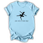 A light blue short-sleeve t-shirt with a black graphic of a ballerina and the text 'just one of those days' printed on the front, displayed against a plain white background.