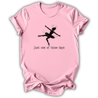 A light pink short-sleeve t-shirt with a black graphic of a ballet dancer and the text 'just one of those days' printed on the front, displayed against a white background.