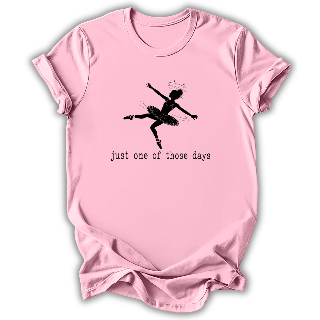 A light pink short-sleeve t-shirt with a black graphic of a ballet dancer and the text 'just one of those days' printed on the front, displayed against a white background.