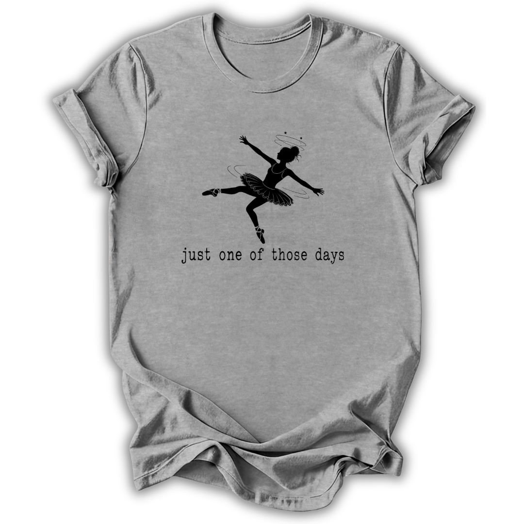 A light gray heather crewneck t-shirt featuring a black graphic of a ballerina in mid-leap with the text 'just one of those days' printed below, displayed on a clean white background.