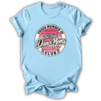 A light blue short-sleeve t-shirt with a circular graphic on the chest that reads 'PROUD MEMBER OF The Bad Dance Moms CLUB'. The graphic features a pink striped background with white and black lettering.