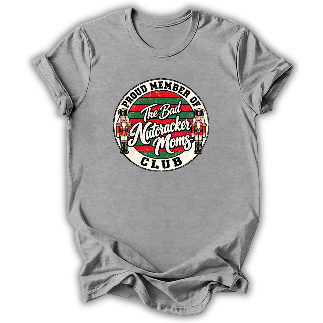 A heather gray short-sleeve t-shirt with a circular graphic on the chest that reads 'PROUD MEMBER OF The Bad Nutcracker Moms CLUB' with nutcracker figures and red, green, and white details.