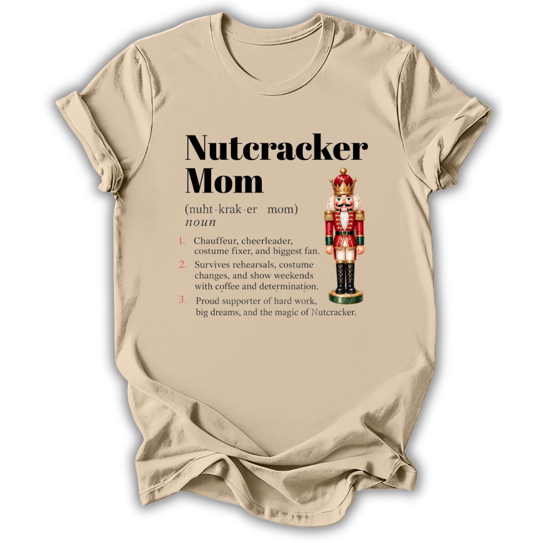 A beige graphic t-shirt laid flat on a white background, featuring a 'Nutcracker Mom' dictionary definition print with a nutcracker illustration.