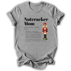 A light gray short-sleeve t-shirt with a 'Nutcracker Mom' dictionary definition graphic printed on the front, featuring a nutcracker illustration and a list of traits, shown on a plain white background.