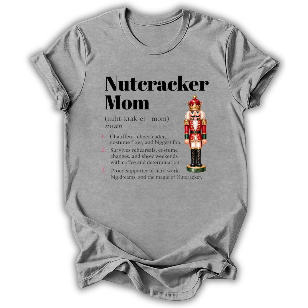 A light gray short-sleeve t-shirt with a 'Nutcracker Mom' dictionary definition graphic printed on the front, featuring a nutcracker illustration and a list of traits, shown on a plain white background.