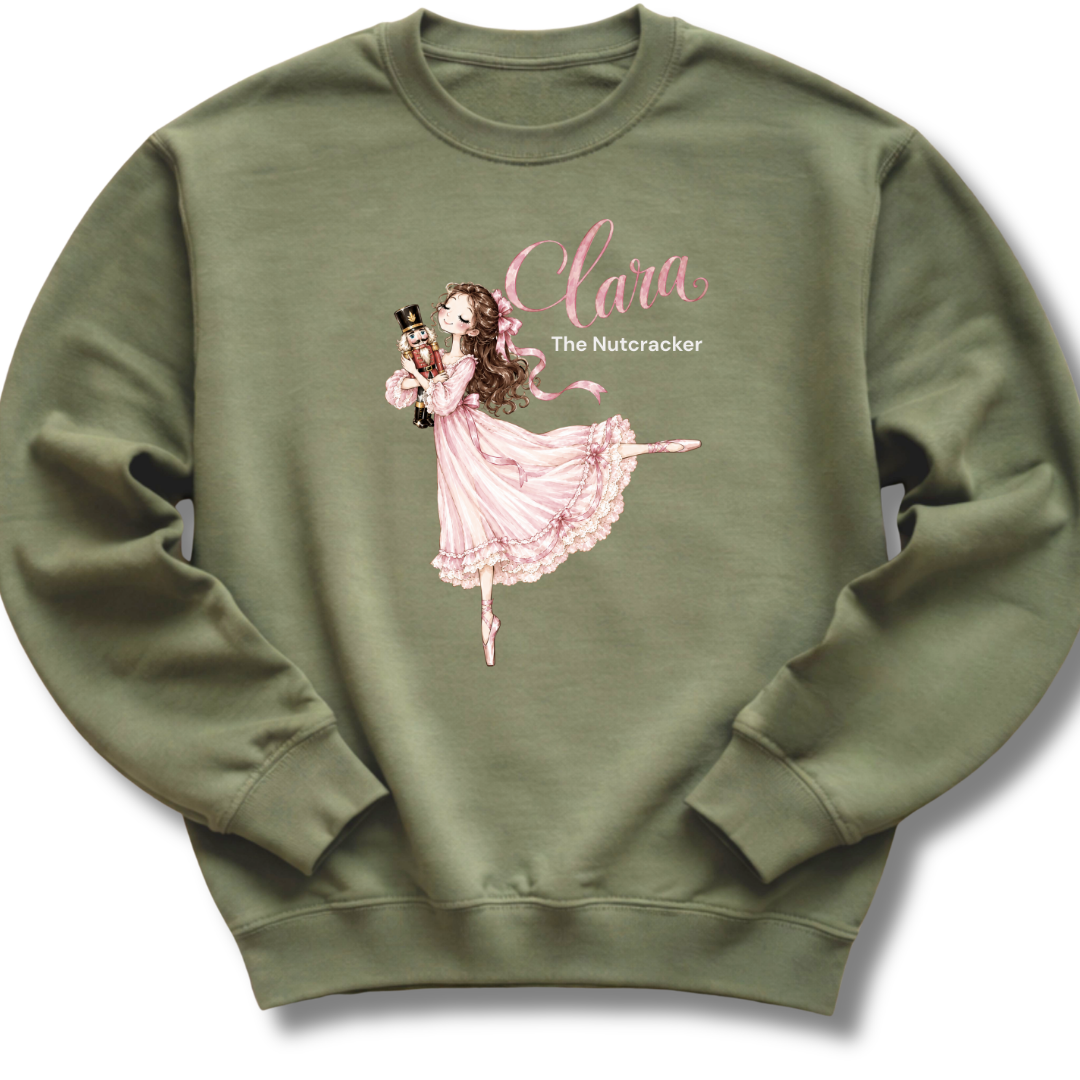 A military green crewneck sweatshirt featuring an illustration of Clara in a graceful pink ballet pose with delicate 'The Nutcracker' lettering.