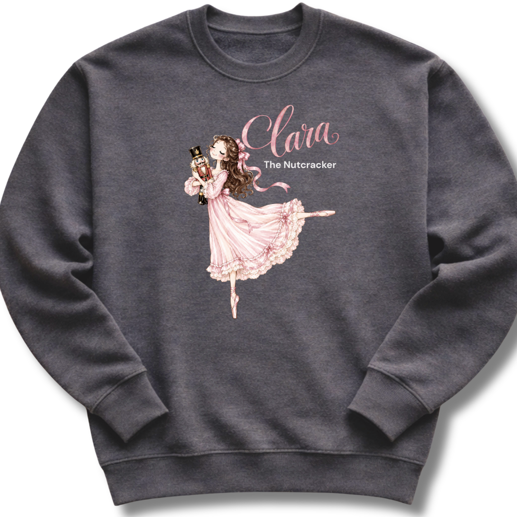 A dark heather gray youth crewneck sweatshirt featuring an illustration of Clara in a graceful pink ballet pose with delicate 'The Nutcracker' lettering.