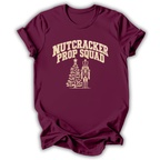 A maroon short-sleeve t-shirt printed with the “Nutcracker Prop Squad” graphic design.