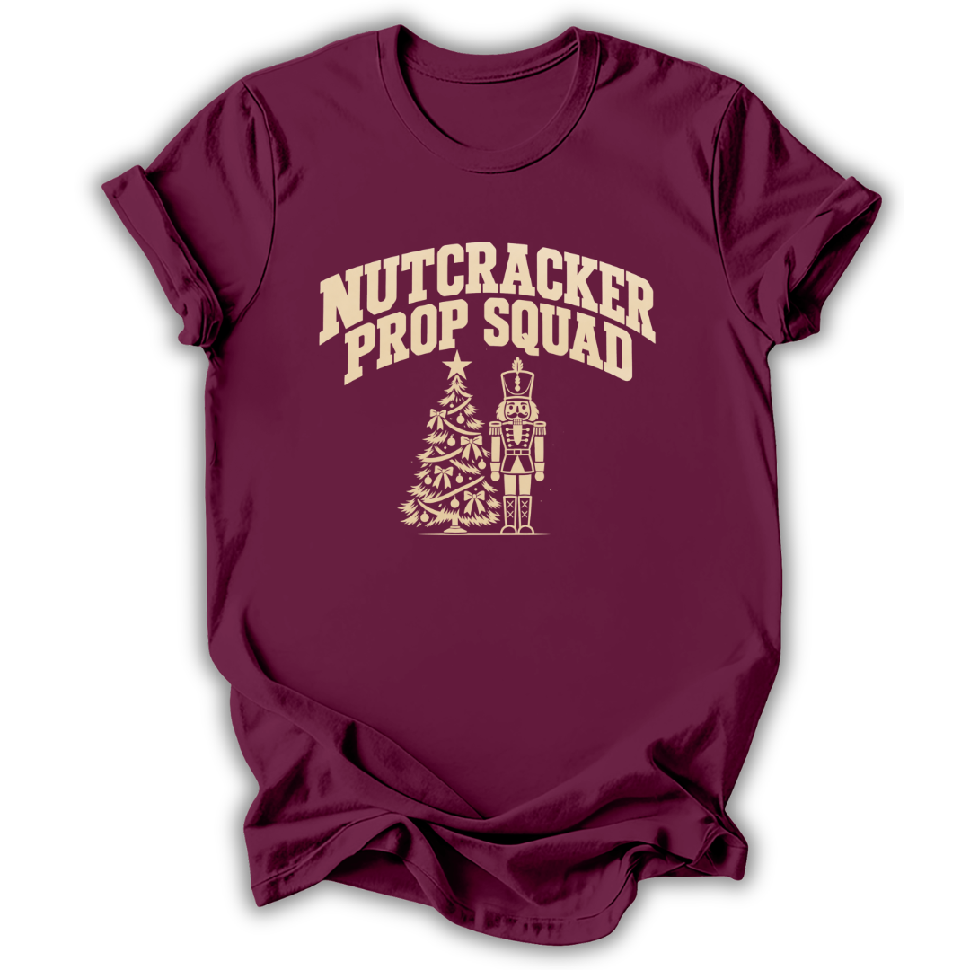 A maroon short-sleeve t-shirt printed with the “Nutcracker Prop Squad” graphic design.