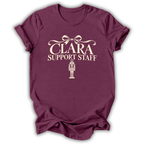 A heather maroon short-sleeve t-shirt printed with the “Clara Support Staff” Nutcracker graphic design.