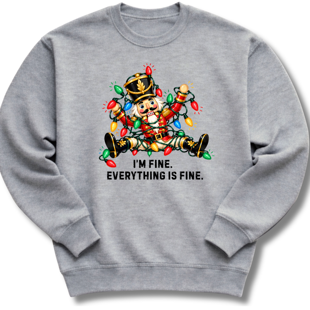 A heather gray crewneck sweatshirt featuring a colorful nutcracker tangled in Christmas lights beneath the words 'I'm fine. Everything's fine.'
