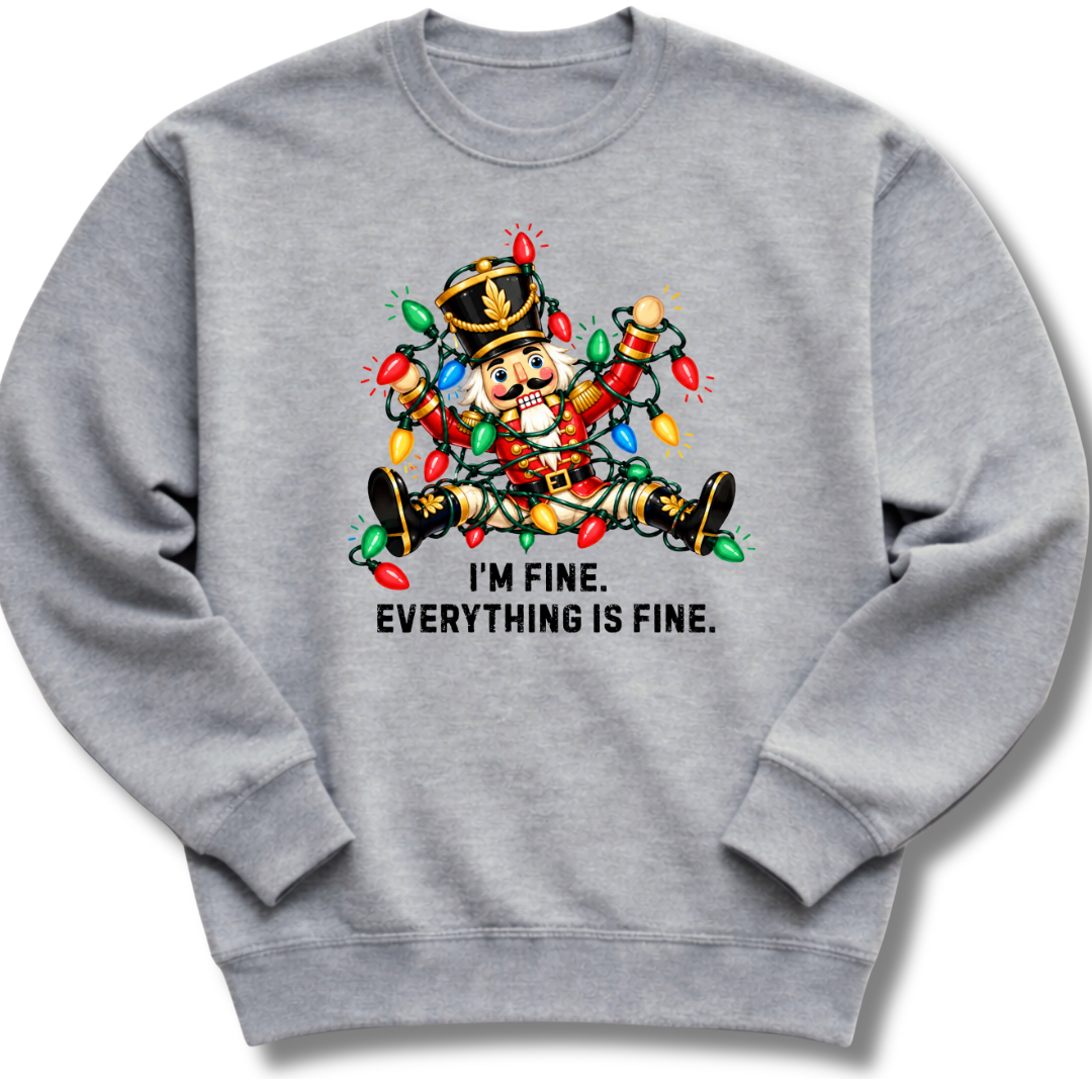 A heather gray crewneck sweatshirt featuring a colorful nutcracker tangled in Christmas lights beneath the words 'I'm fine. Everything's fine.'