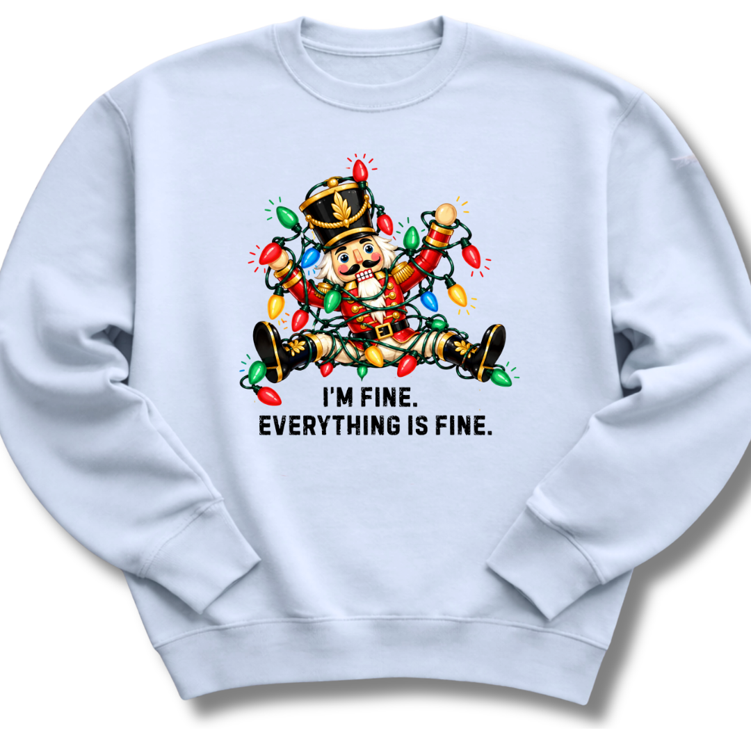 A light blue crewneck sweatshirt featuring a colorful nutcracker tangled in Christmas lights beneath the words 'I'm fine. Everything's fine.'
