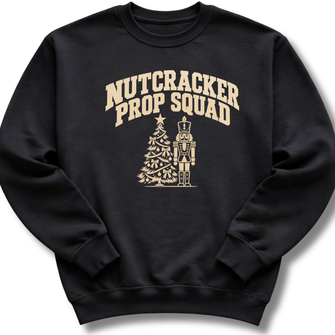 A black crewneck sweatshirt featuring a vintage-inspired 'Nutcracker Prop Squad' design with a nutcracker soldier and a Christmas tree.