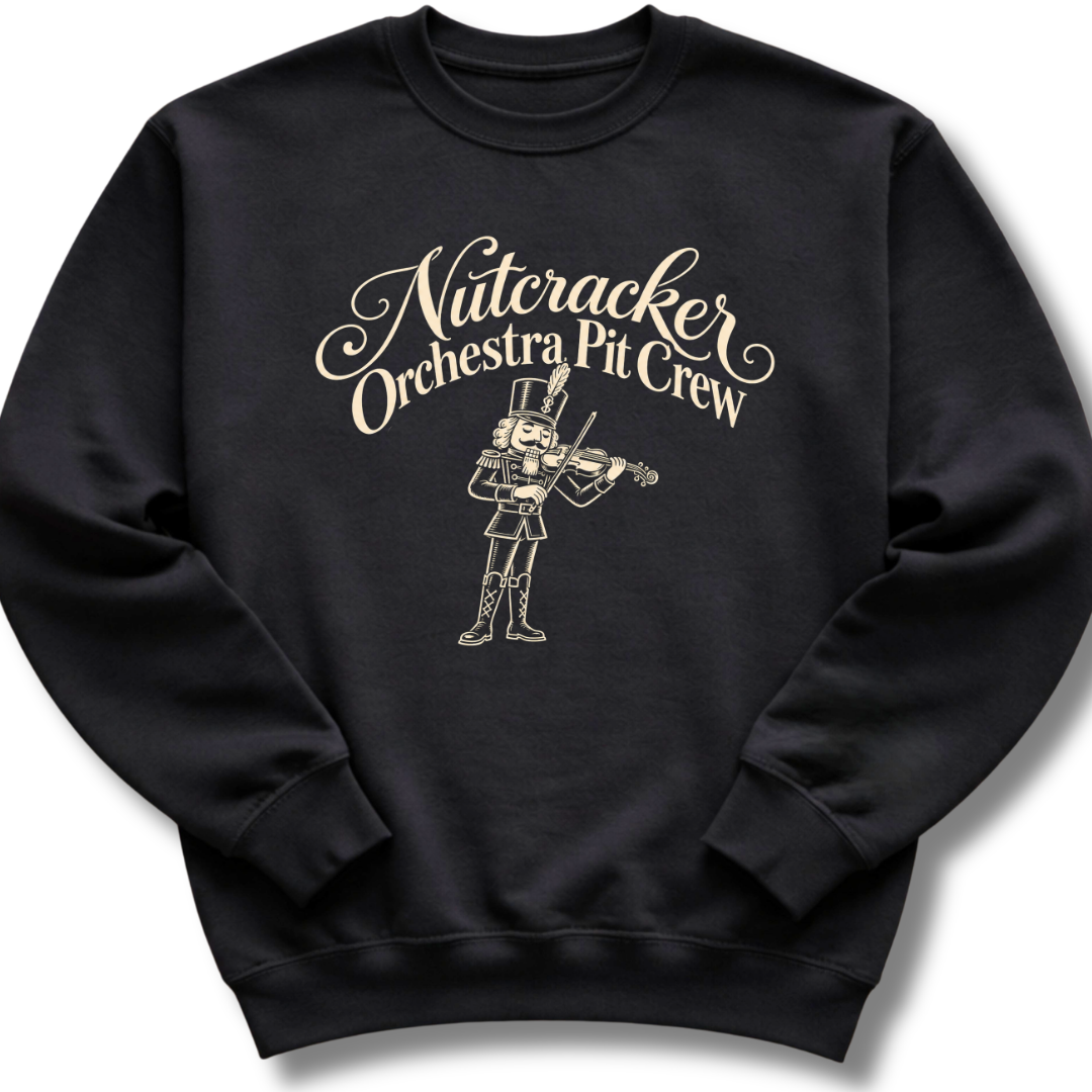 A black crewneck sweatshirt featuring a 'Nutcracker Orchestra Pit Crew' design with a classic nutcracker and elegant script lettering.