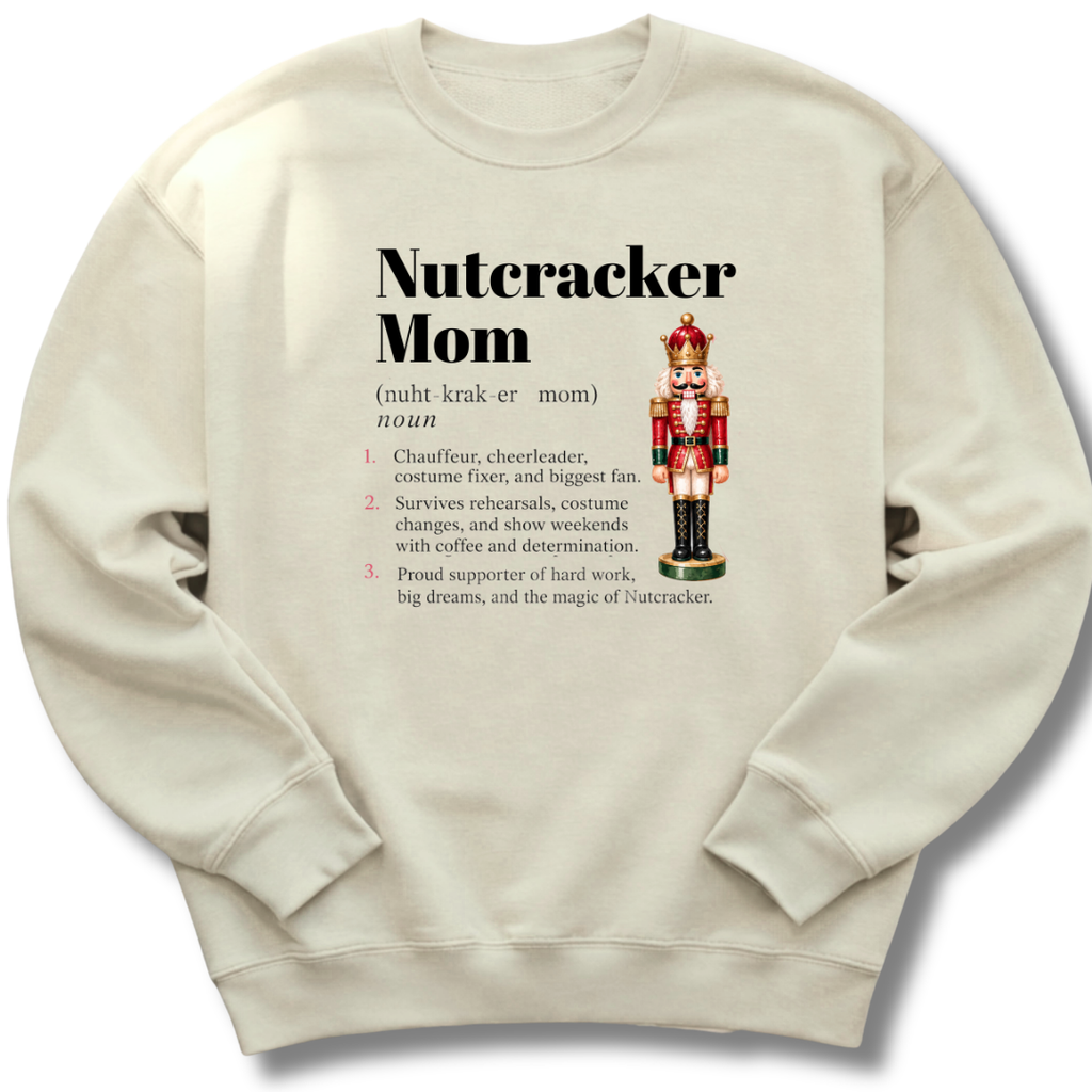A sand-colored crewneck sweatshirt featuring a dictionary-style definition of 'Nutcracker Mom'.