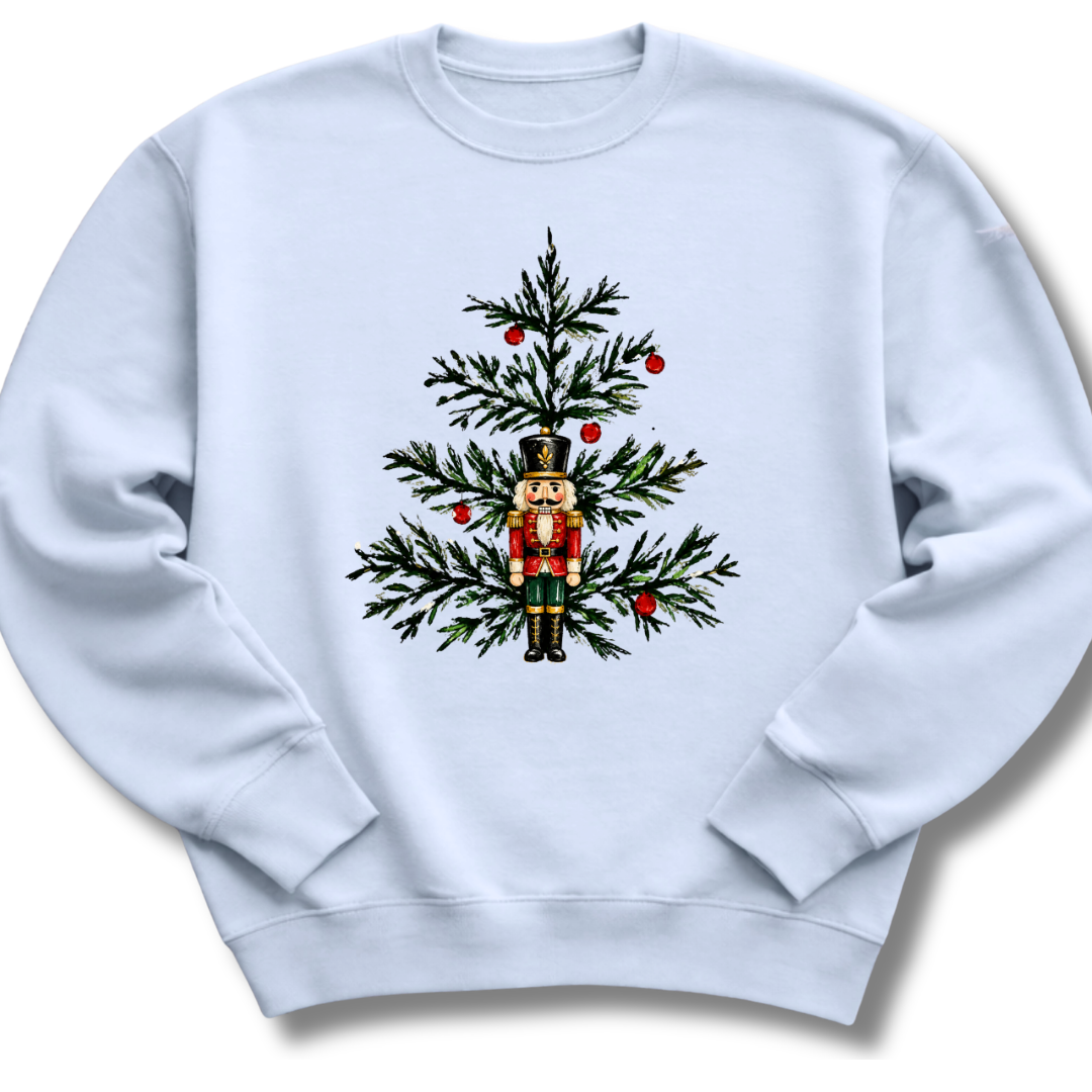A light blue crewneck sweatshirt featuring a nutcracker nestled among evergreen branches and bright red winter berries.