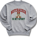 A heather gray crewneck sweatshirt featuring a playful nutcracker graphic with the words 'Nutcracker Is My Sport'.