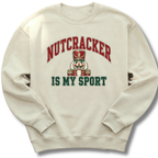 A sand-colored crewneck sweatshirt featuring a playful nutcracker graphic with the words 'Nutcracker Is My Sport'.
