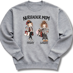 A heather gray crewneck sweatshirt featuring an illustrated 'Nutcracker Mom' design with two characters, one ready for Friday's performance and one twirling into Sunday.