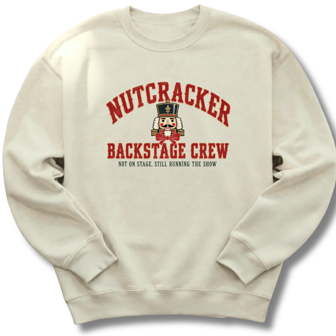 A sand-colored crewneck sweatshirt featuring a vintage-inspired nutcracker with 'Backstage Crew' lettering.
