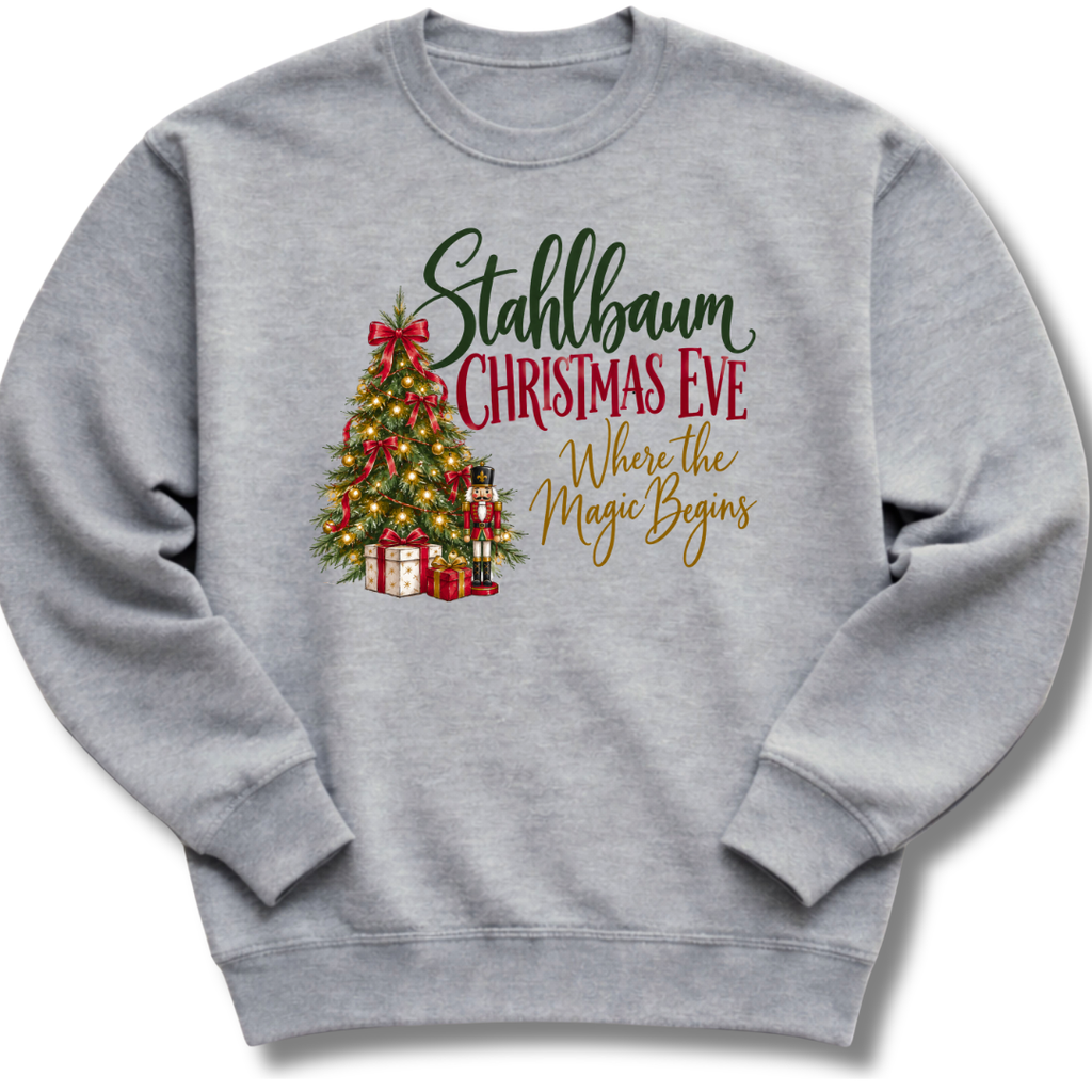 A heather gray crewneck sweatshirt featuring a decorated vintage-style Christmas tree with the words 'Stahlbaum Christmas Eve, Where the Magic Begins'.
