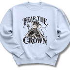 A light blue crewneck sweatshirt featuring a crowned, sword-bearing mouse in detailed black artwork beneath the words 'FEAR THE CROWN'.