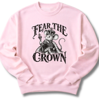 A light pink crewneck sweatshirt featuring a crowned, sword-bearing mouse in detailed black artwork beneath the words 'FEAR THE CROWN'.