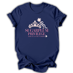 A navy blue short-sleeve t-shirt with a graphic on the front featuring a white crown, a pink ribbon, and the text 'SUGARPLUM PRIVILEGE' and 'SOME OF US ARE FLOWERS' in pink and white.
