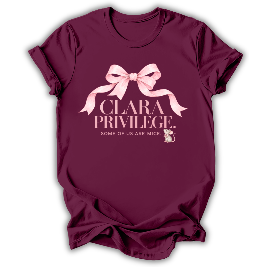 A maroon short-sleeve t-shirt with a pink graphic on the front featuring a bow, the text 'CLARA PRIVILEGE.', and 'SOME OF US ARE MICE.