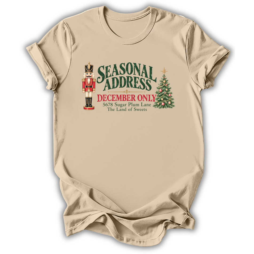 A sand beige short-sleeve t-shirt printed with the “Seasonal Address” graphic design.