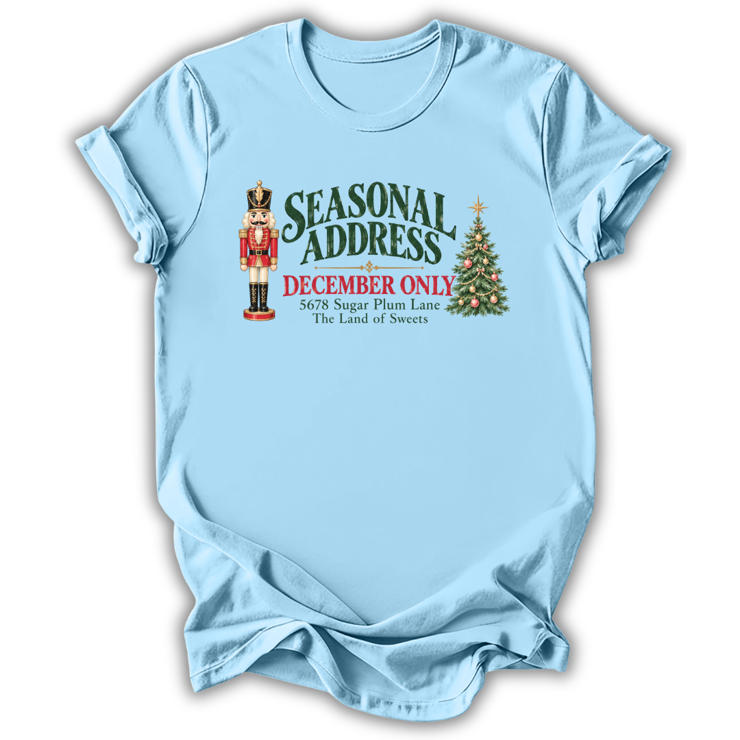 A light blue short-sleeve t-shirt printed with the “Seasonal Address” graphic design.