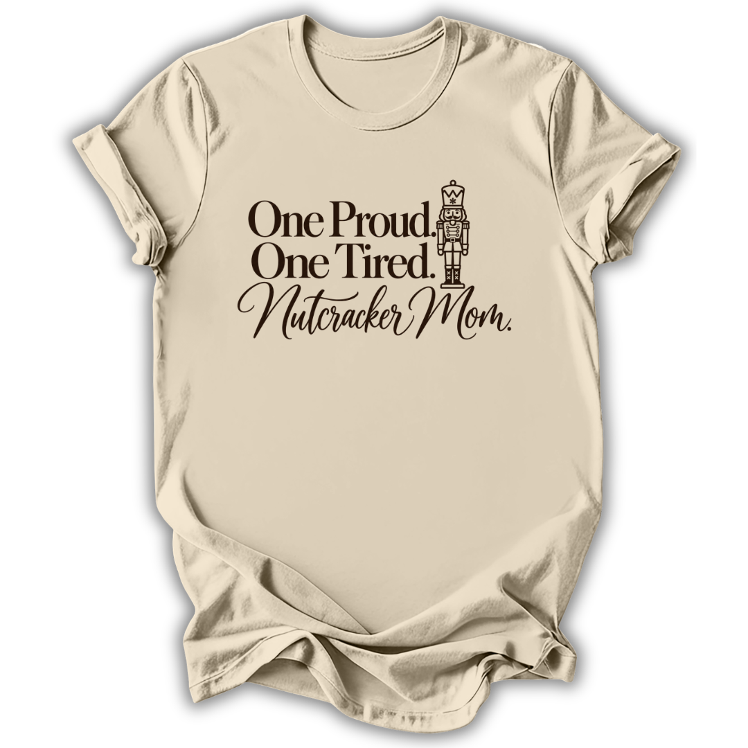 A natural cream short-sleeve t-shirt printed with the “Proud & Tired Nutcracker Mom” graphic design.