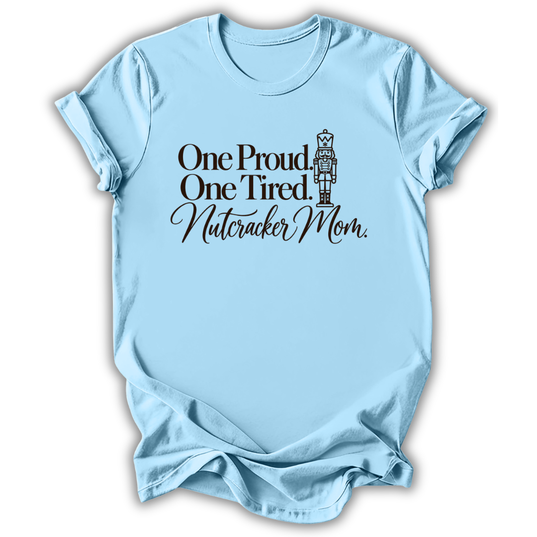 A light blue short-sleeve t-shirt printed with the “Proud & Tired Nutcracker Mom” graphic design.