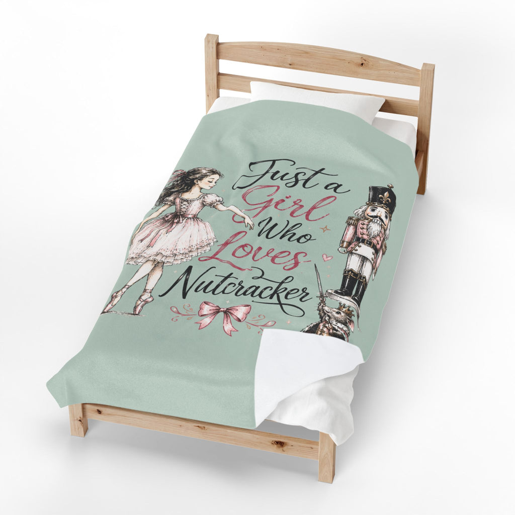 A mint green bedding set on a wooden toddler bed, featuring a printed design with a ballerina, a nutcracker, and the text 'Just a Girl Who Loves Nutcracker' in black and pink script.