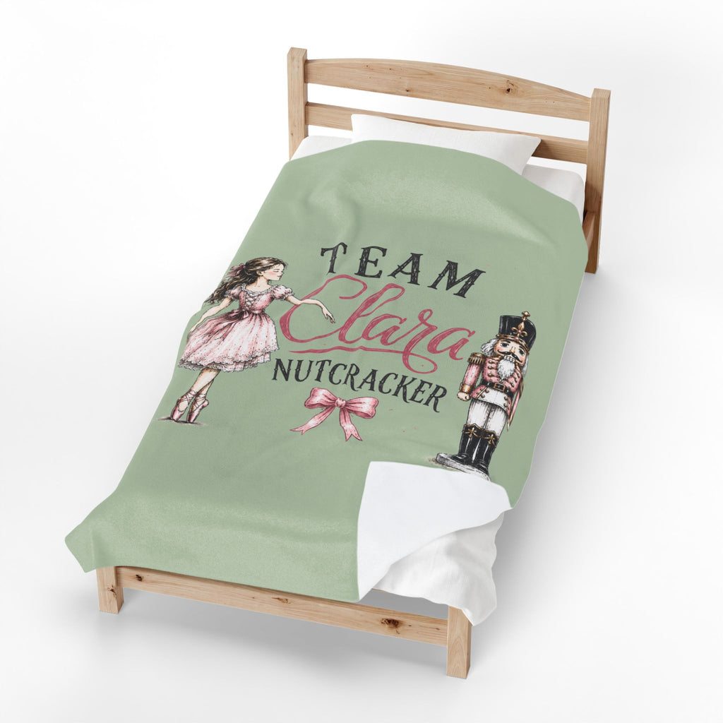 A personalized bedding set featuring a sage green duvet cover with a custom 'Team Clara Nutcracker' graphic, styled on a wooden toddler bed with white sheets.