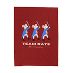 A red rectangular fabric item, likely a towel or blanket, featuring a graphic of three cartoon rats dressed as Nutcracker soldiers with swords, above the text 'TEAM RATS' and 'The Nutacker'.