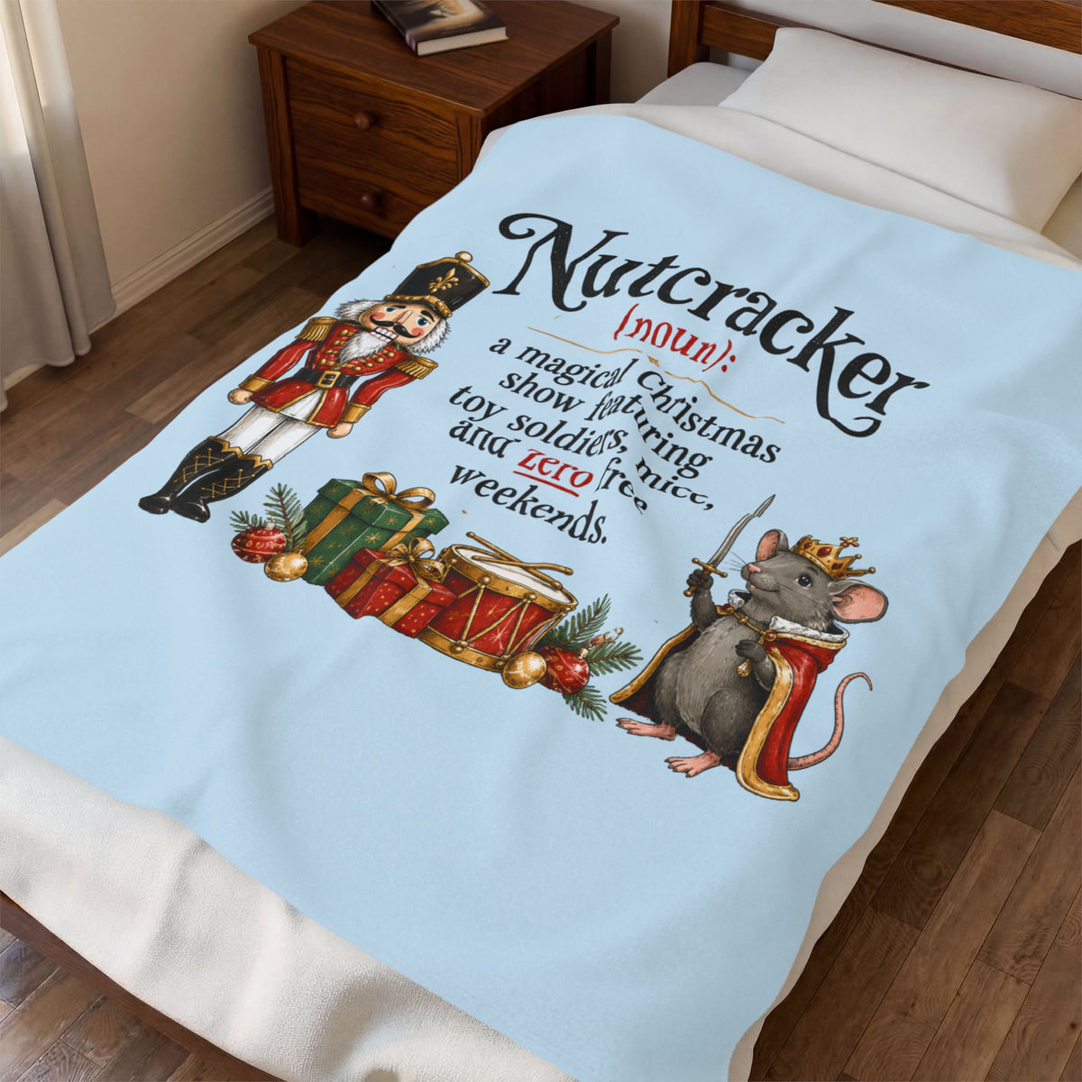 A light blue bedding set, including a comforter and matching pillowcase, styled on a bed in a bedroom. The comforter features a festive Christmas-themed graphic with a nutcracker, a mouse dressed as a king, and a definition of the word 'Nutcracker'.
