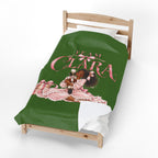 A green bedding set, including a duvet cover and pillowcase, displayed on a wooden toddler bed. The duvet cover features a graphic of a young girl in a pink dress with the text 'TEAM CLARA' in pink script.