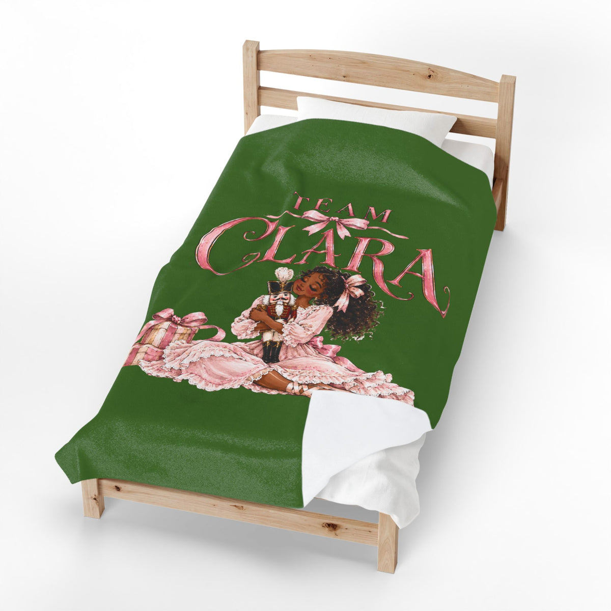 A green bedding set, including a duvet cover and pillowcase, displayed on a wooden toddler bed. The duvet cover features a graphic of a young girl in a pink dress with the text 'TEAM CLARA' in pink script.